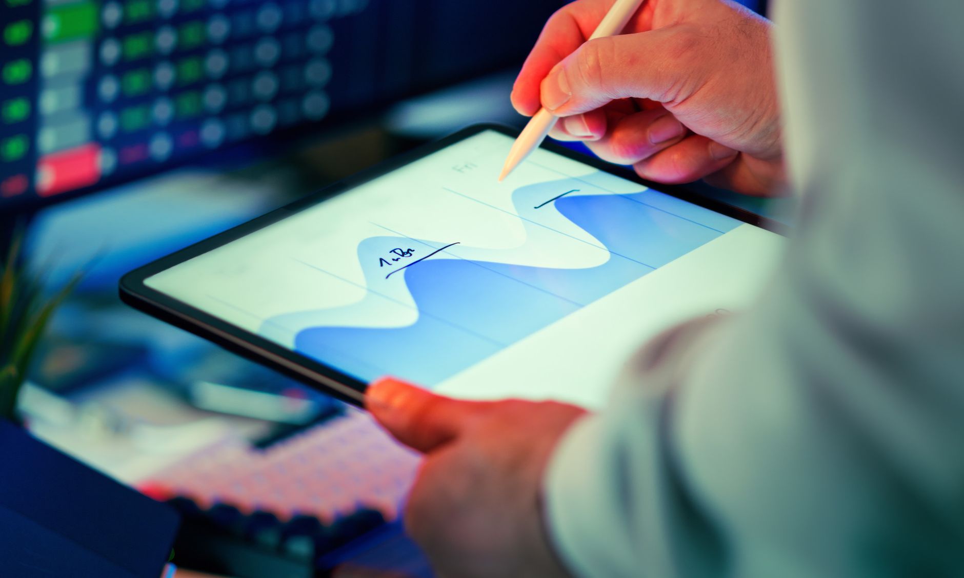 Professional analyzing data chart on a tablet with stylus in an office setting.