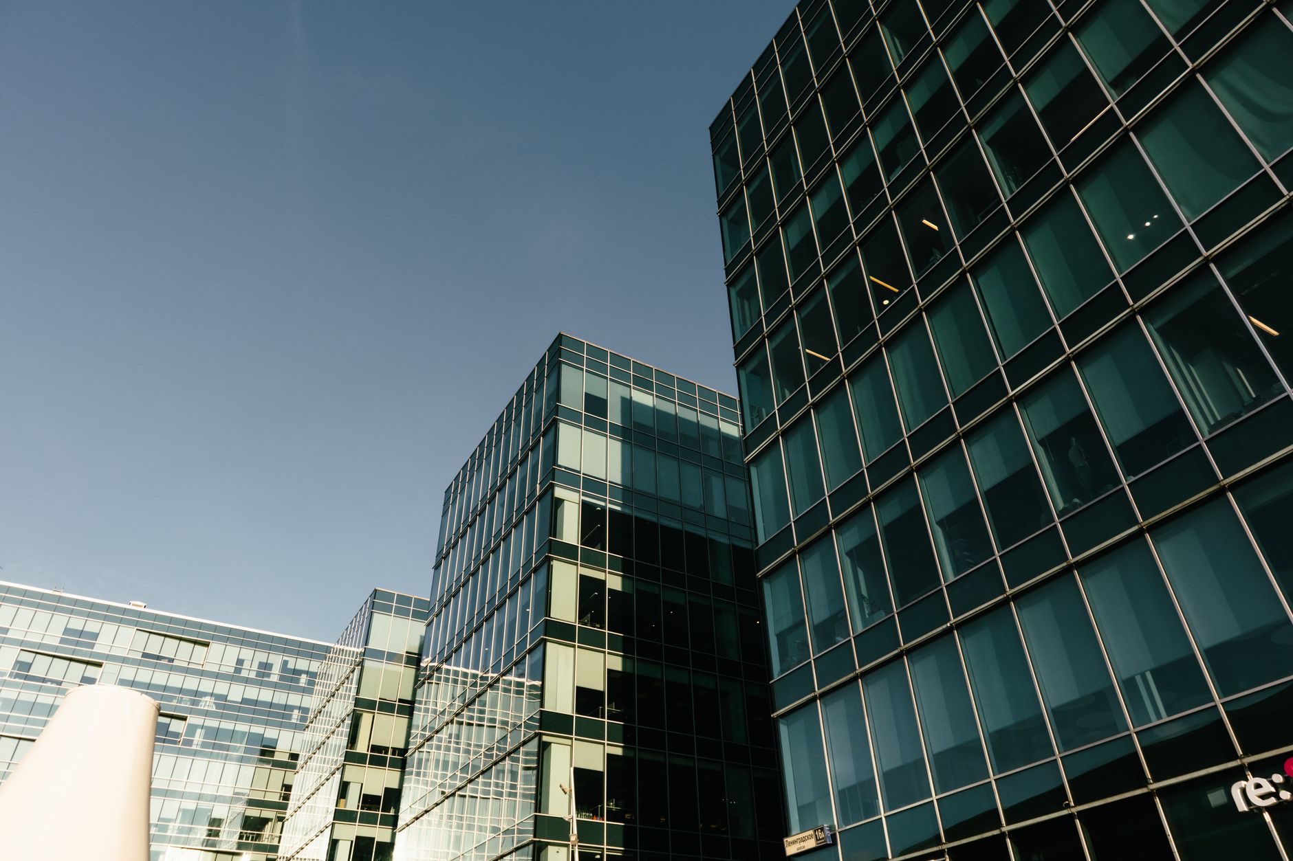 Elegant modern glass office buildings with reflective windows under a clear blue sky, showcasing urban architecture.