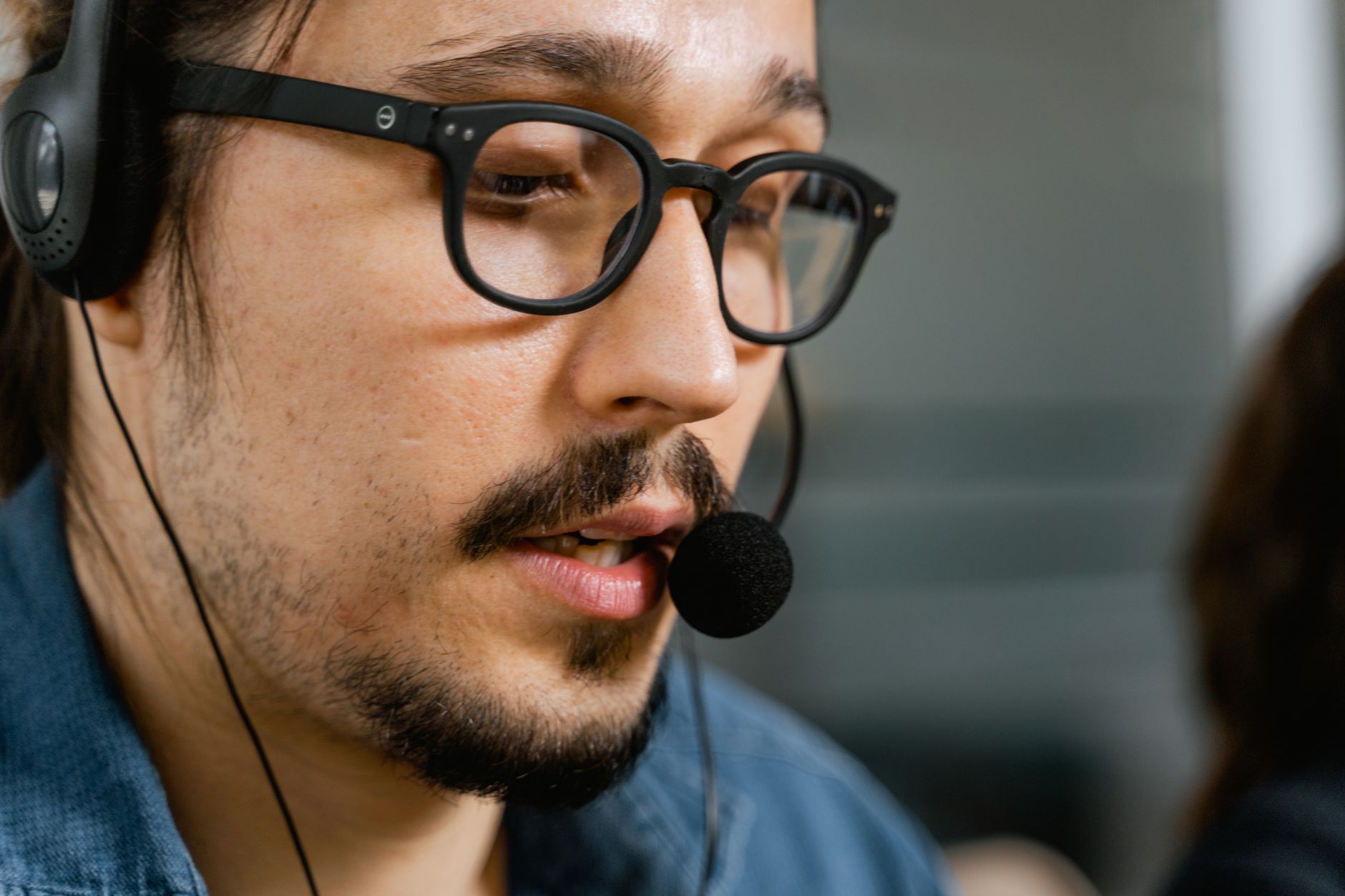 Close-up of a call center agent with a headset and eyeglasses providing customer support.