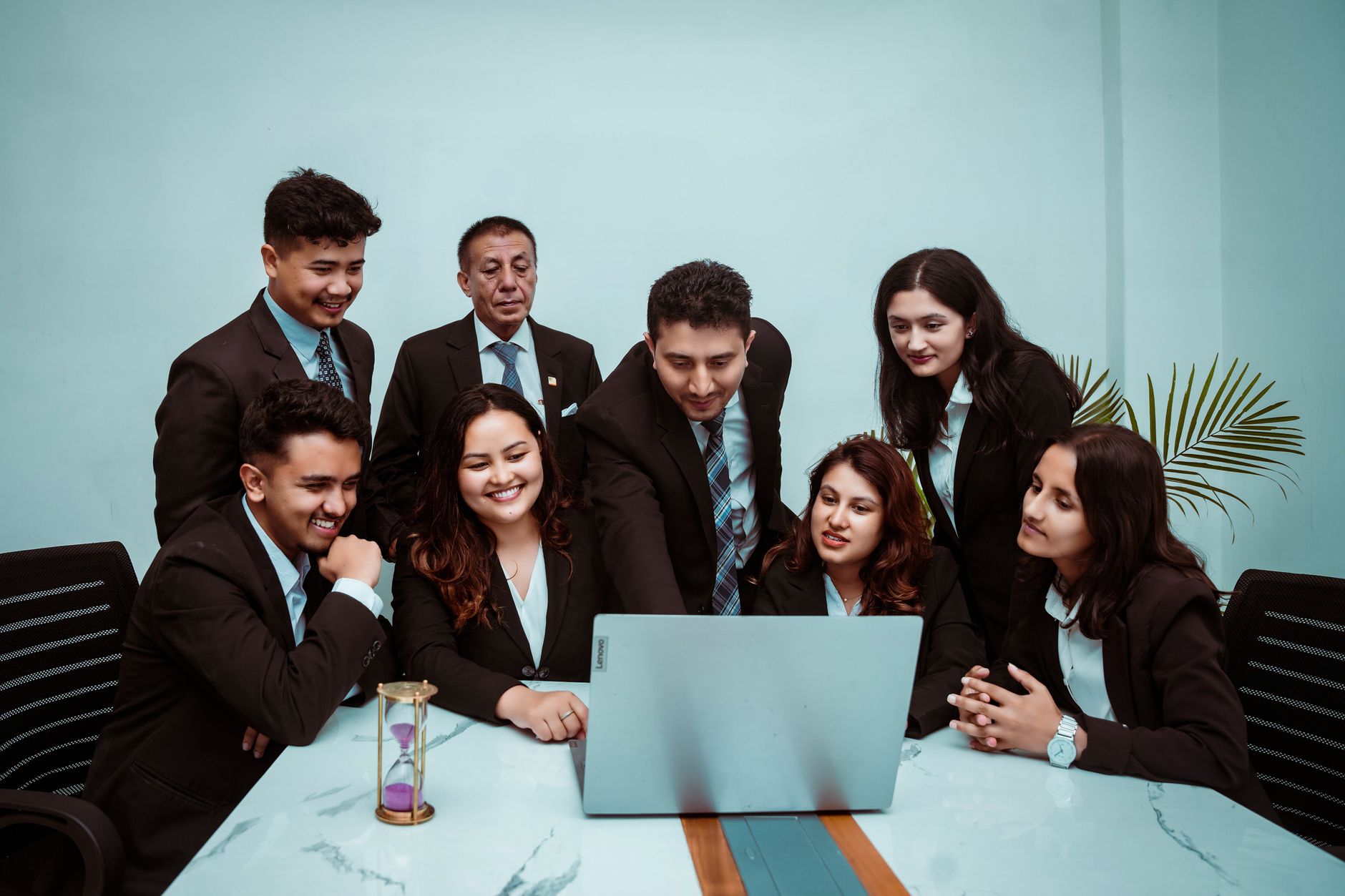 A diverse team of professionals collaborating around a laptop in a modern office setting.